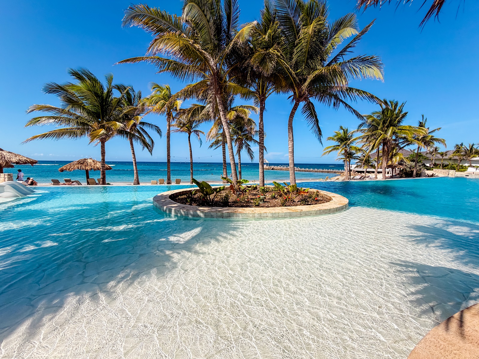 Tropical pool at The Tryall Club with palm trees, ocean views, and sun loungers.