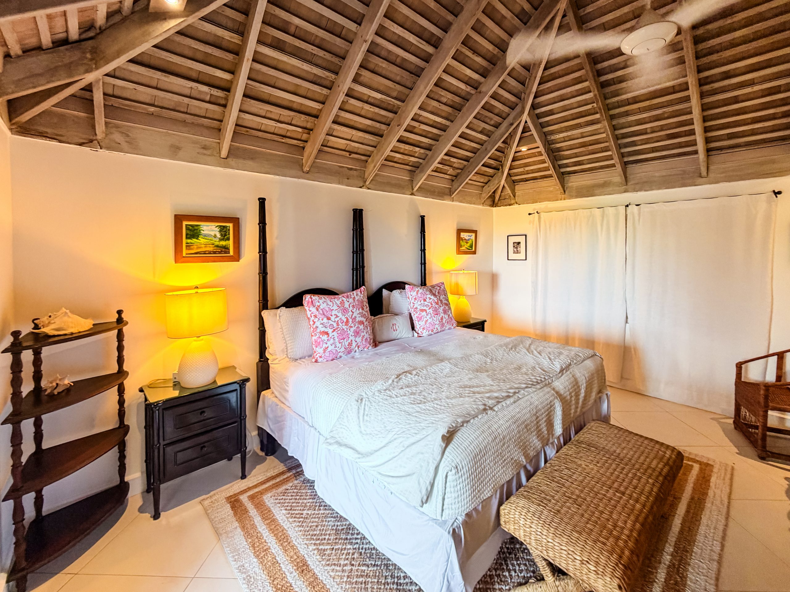 ropical luxury villa suite with four‑poster bed, wooden doors, vaulted ceiling, and Caribbean décor at Coconut Cottage.