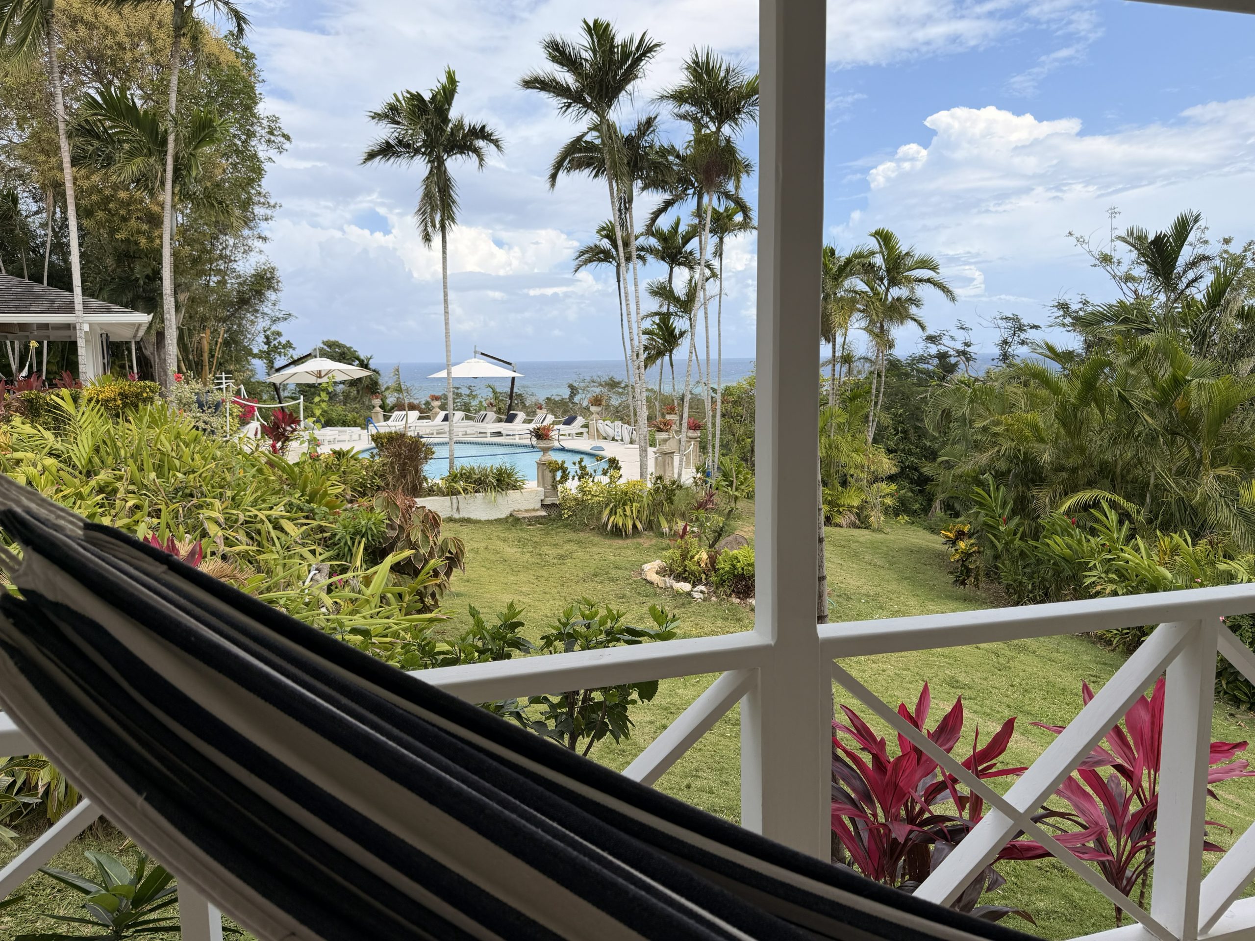 Hammock on a verandah at Coconut Cottage Montego Bay overlooking tropical gardens, pool and Caribbean Sea.