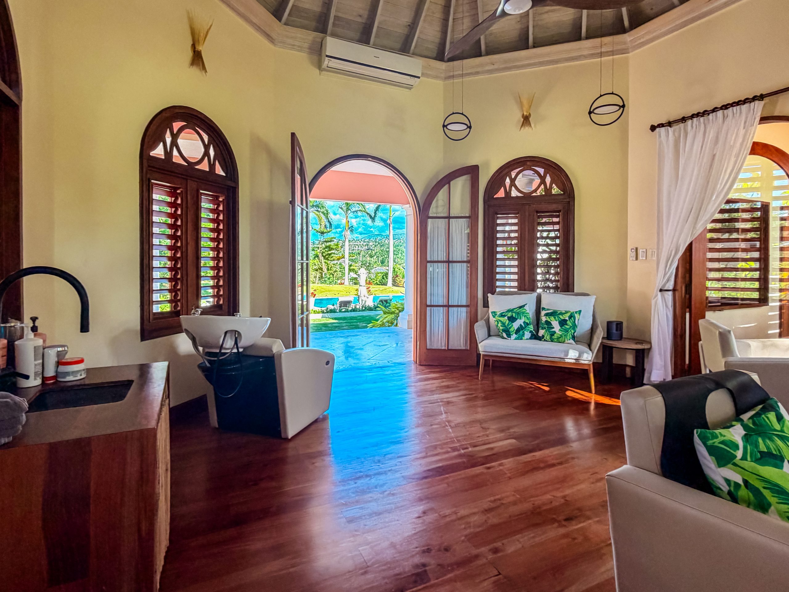 Spa room at The Tryall Club with tropical decor, wooden shutters, and a view of the pool and palm trees.