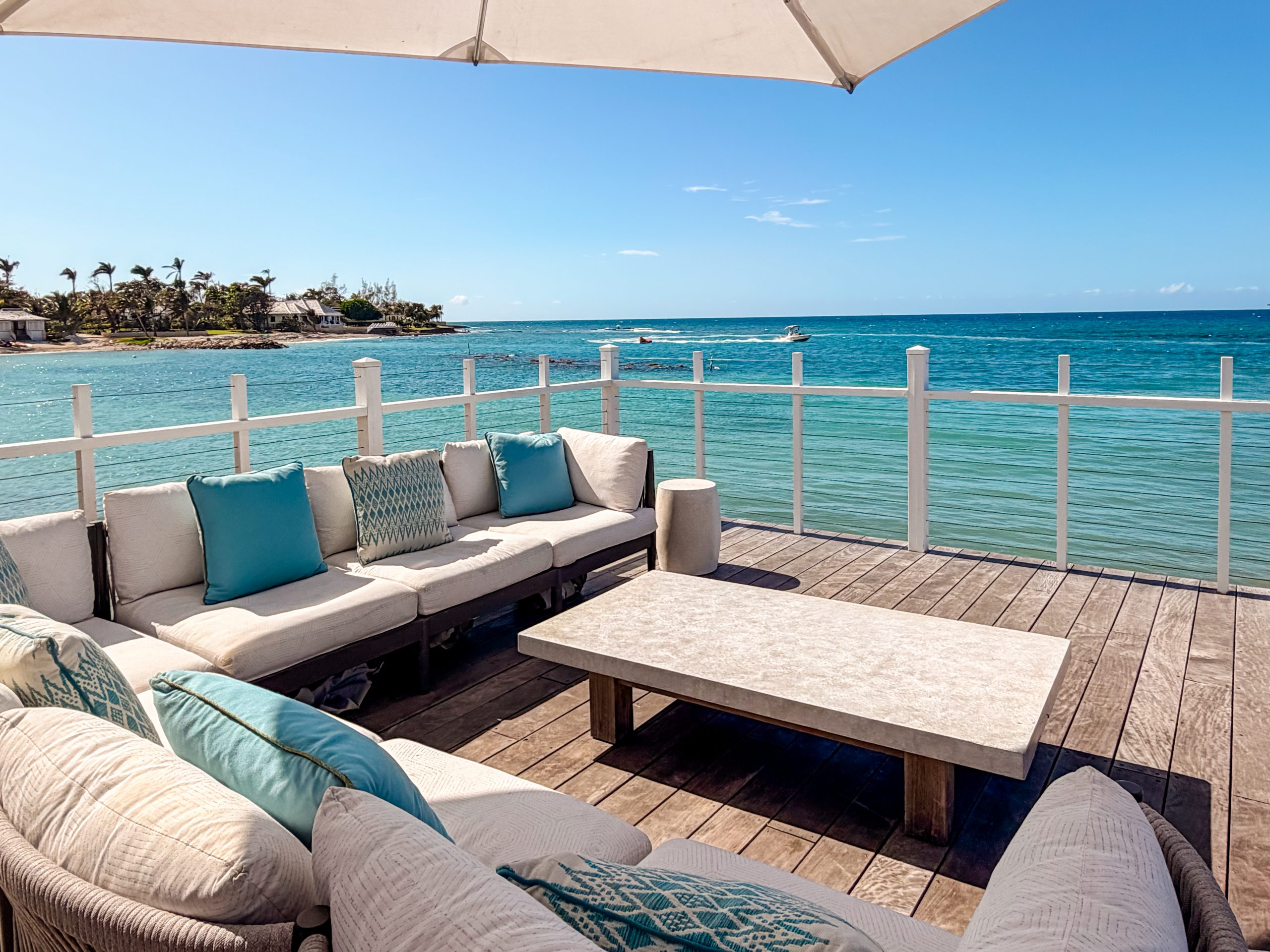 Oceanfront deck at the Tryall Beach Club with cushioned seating, umbrella shade and views of turquoise Caribbean water.