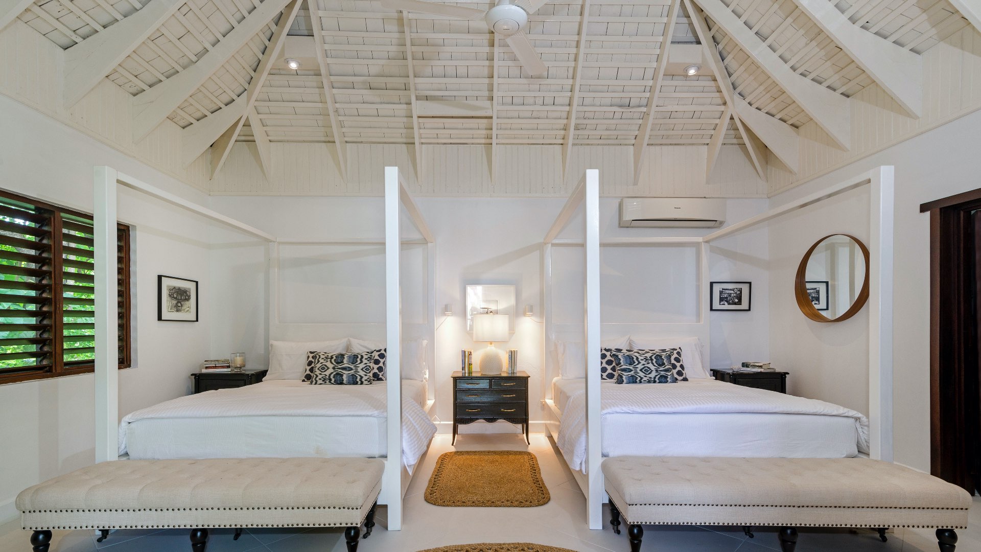 Airy Coconut Cottage bedroom with twin four‑poster beds, white bedding, beige benches, and soft neutral tones that create a calm, balanced atmosphere.