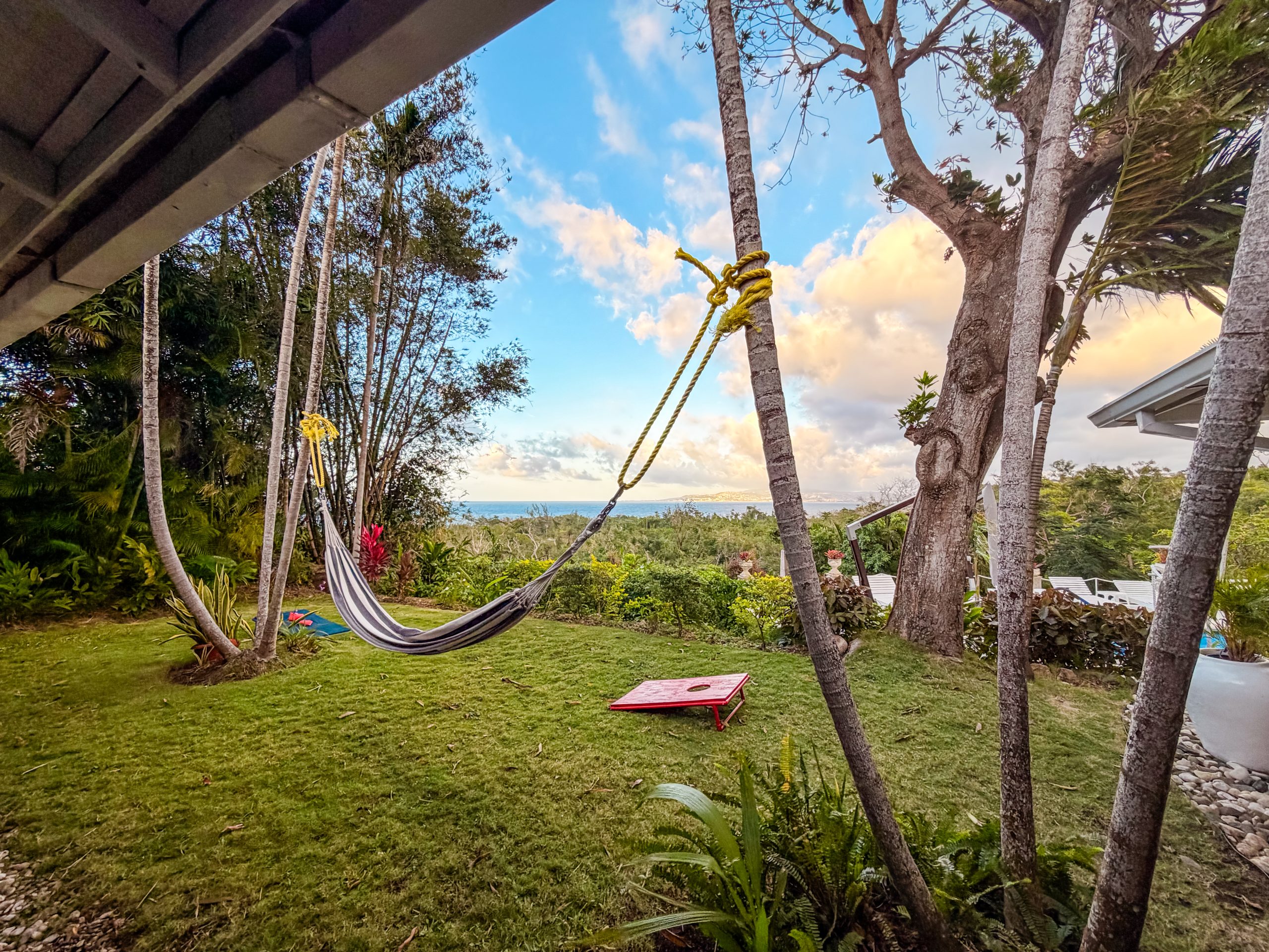 Hammock strung between two trees overlooking lush tropical gardens and distant hillside views at Coconut Cottage villa in Montego Bay.