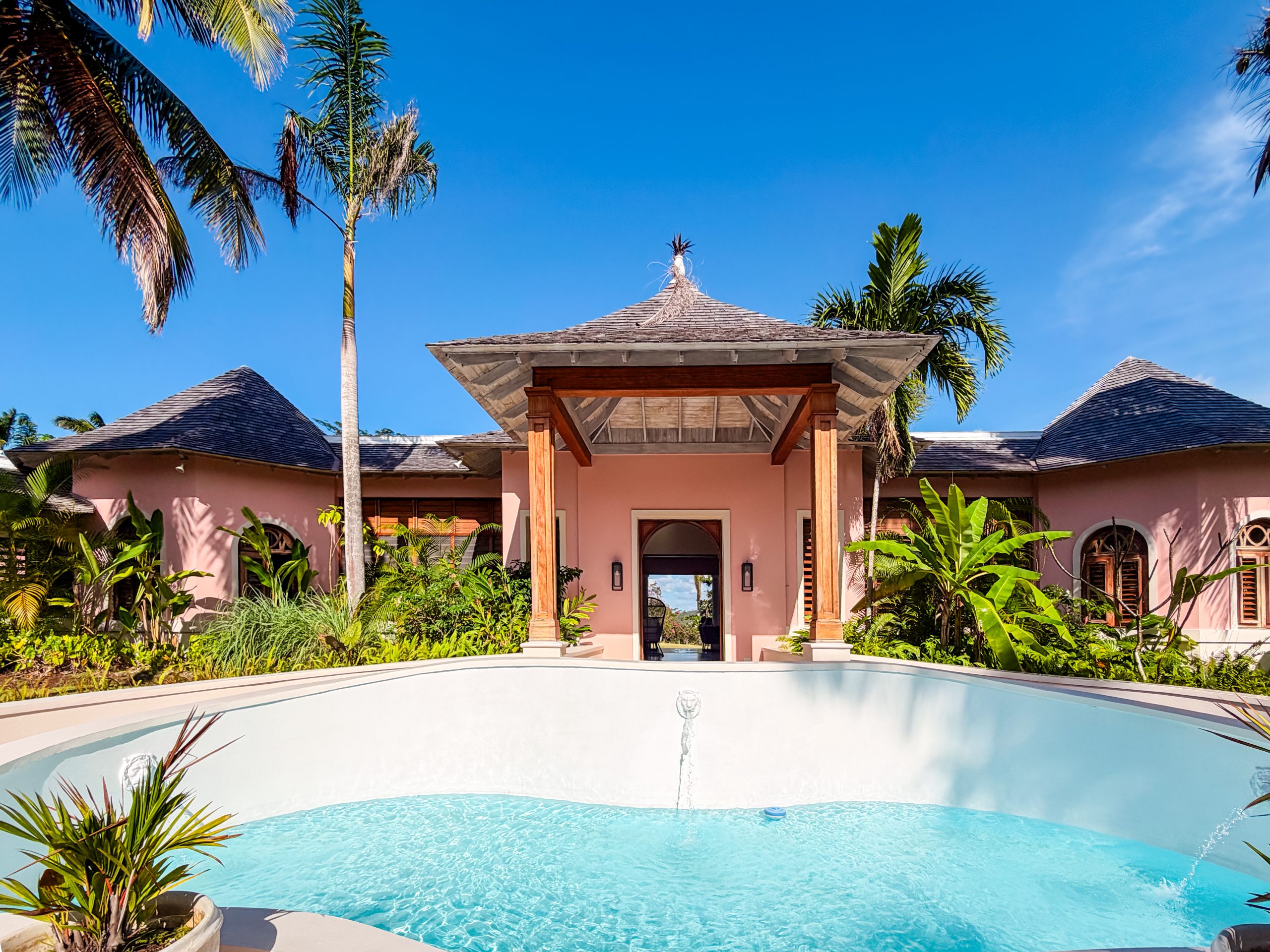 Tropical pink villa exterior at Tryall Club with lush gardens, palm trees and a tranquil water feature.